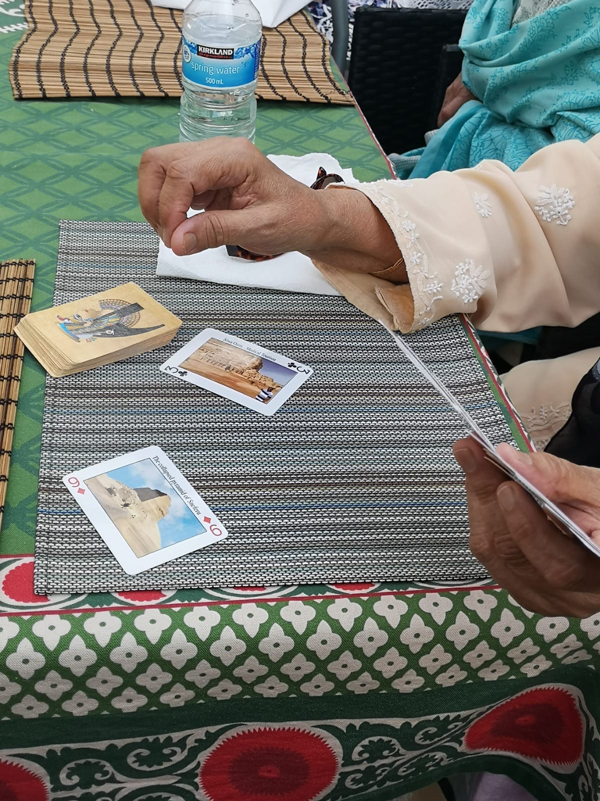 a persons hand over a table playing a card game